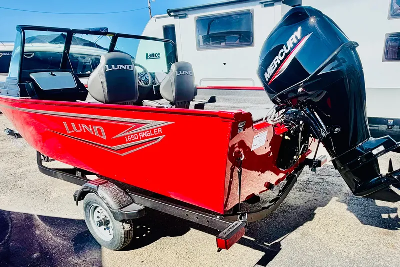 Slide: The Image of 2026 Lund 1650 Angler Sport boat with Mercury engine, red exterior, parked on trailer. - 3