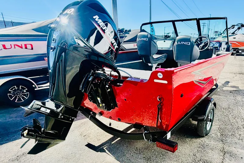 Slide: The Image of 2026 Lund 1650 Angler Sport boat with Mercury engine, vibrant red exterior, parked outdoors. - 5
