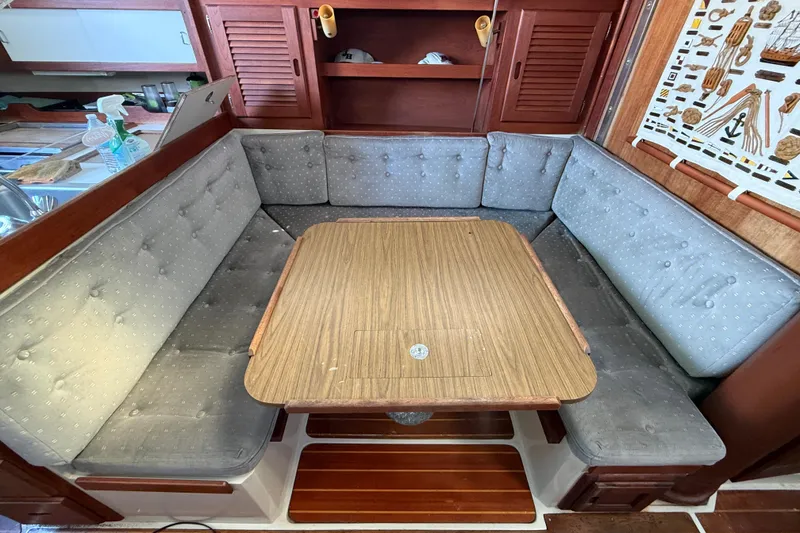 Slide: The Image of Cozy dining area in a 1987 Catalina 36 sailboat with cushioned seating and wooden table. - 23