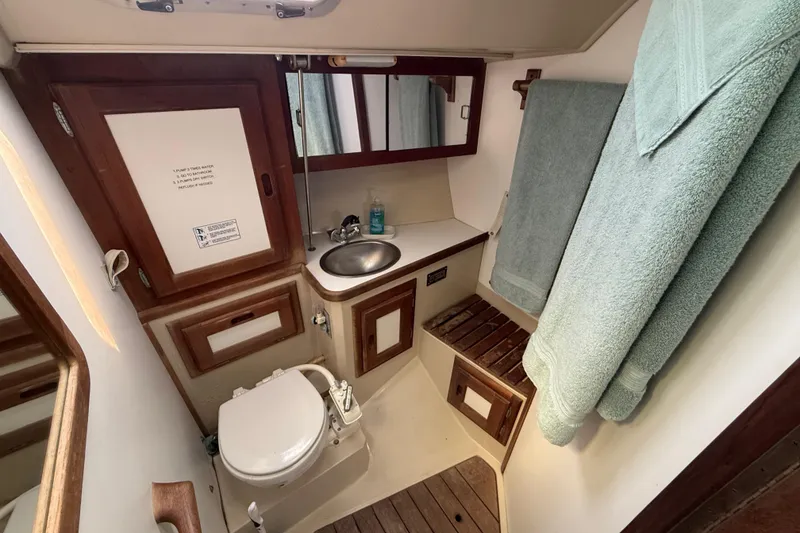 Slide: The Image of Bathroom interior of a 1987 Catalina 36 sailboat with sink, toilet, and wooden accents. - 26