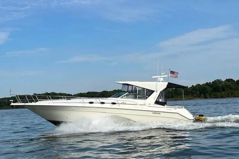 The Image of 1994 Sea Ray 440 Sundancer yacht docked at marina, featuring sleek design and American flag. - 0
