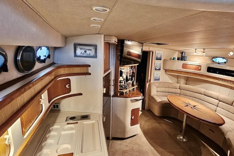 Slide: The Image of 1994 Sea Ray 440 Sundancer interior with cozy seating and nautical-themed table. - 16