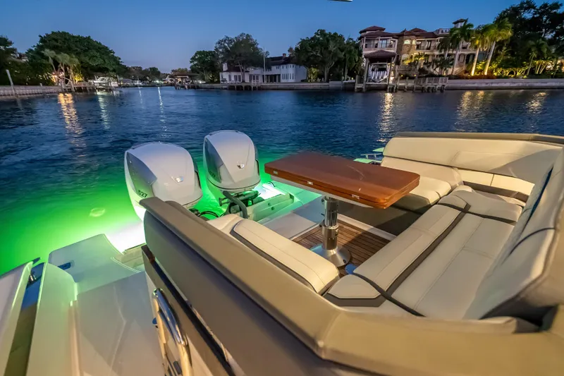 Slide: The Image of 2019 Tiara Yachts 38 LS with illuminated seating area and dual engines at sunset. - 28