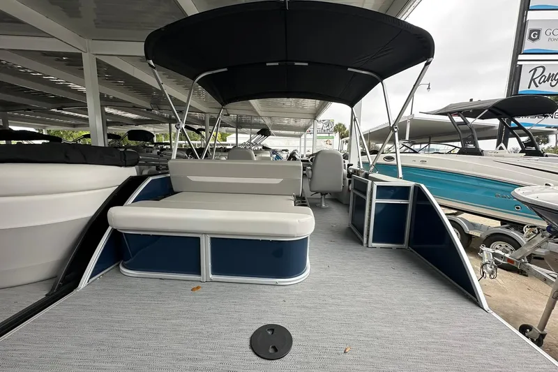 Slide: The Image of 2026 Sweetwater EX 2286 SFLX pontoon boat with canopy, docked under shelter. - 20