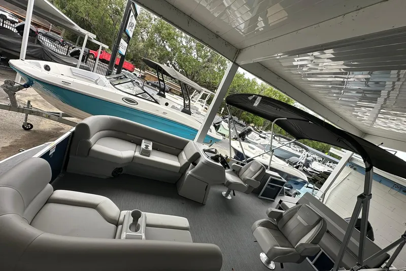 Slide: The Image of 2026 Sweetwater EX 2286 SFLX pontoon boat with spacious seating and canopy in a showroom. - 5