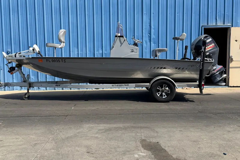 The Image of 2024 Xpress H190B Bay boat on trailer, parked by blue building. - 0
