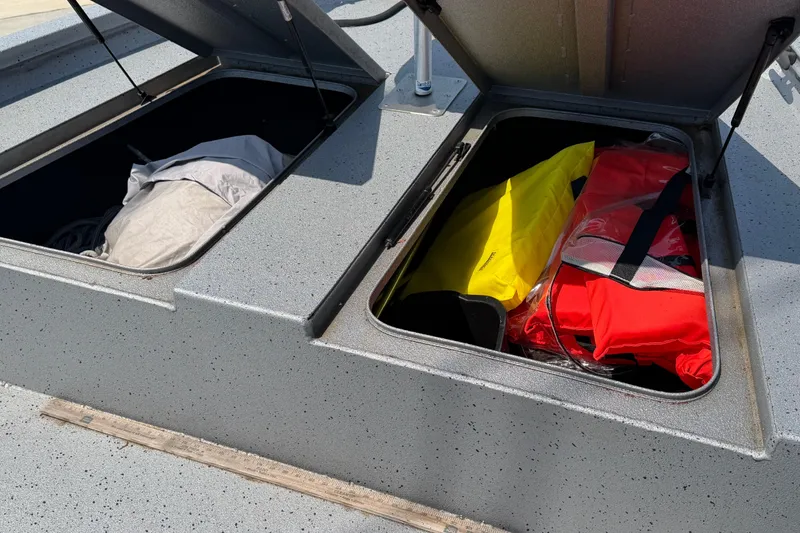 Slide: The Image of Open storage compartments on 2024 Xpress H190B Bay boat with life jackets and gear. - 14