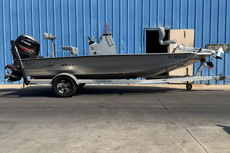 Slide: The Image of 2024 Xpress H190B Bay boat on trailer, parked by blue building. - 4