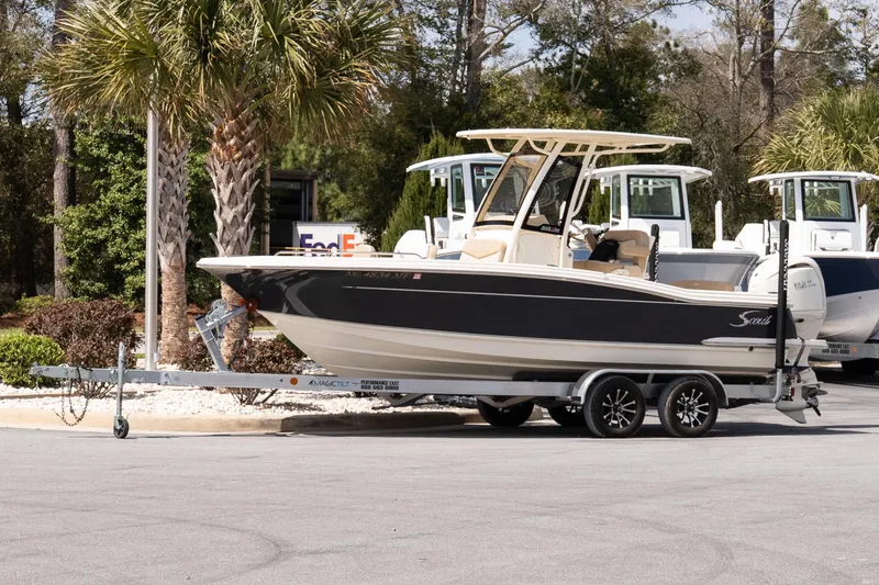 The Image of 2026 Scout 215 XSF boat on trailer, parked near palm trees. - 1