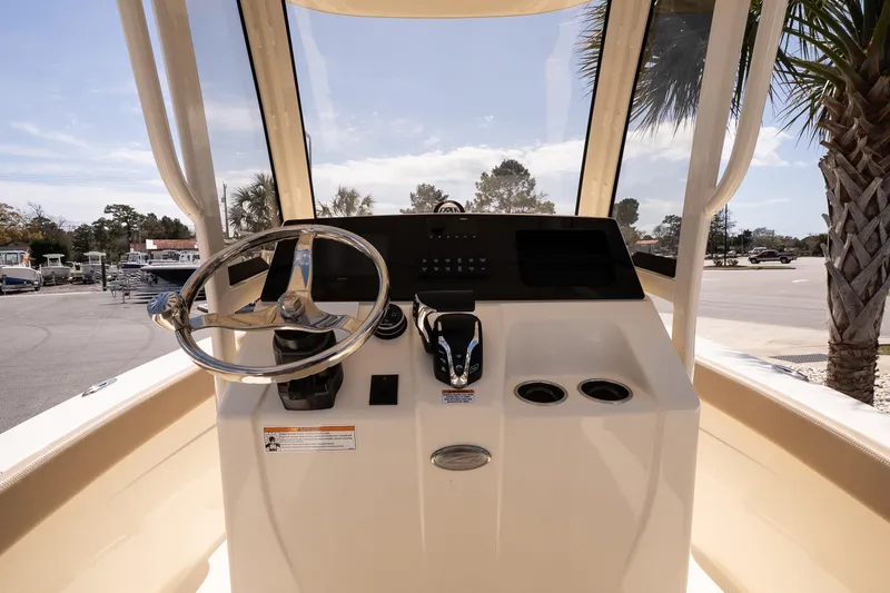 Slide: The Image of 2026 Scout 215 XSF boat helm with steering wheel and controls, parked outdoors. - 10