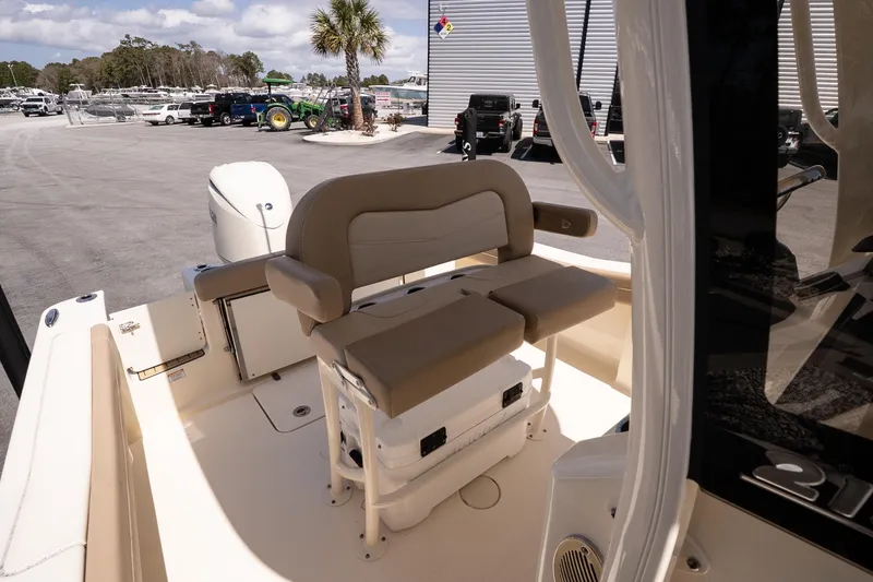 Slide: The Image of 2026 Scout 215 XSF boat interior with seating and storage, parked outdoors. - 12