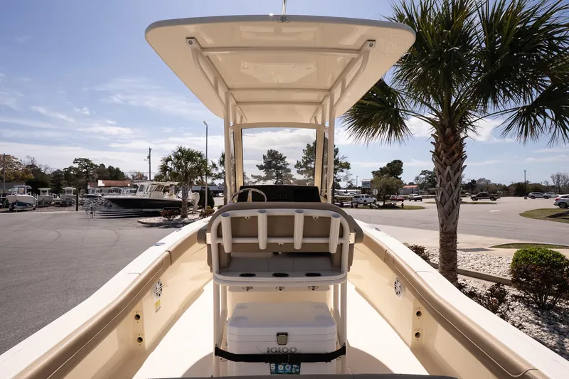 Slide: The Image of 2026 Scout 215 XSF boat with T-top, parked near palm trees in a sunny marina. - 7