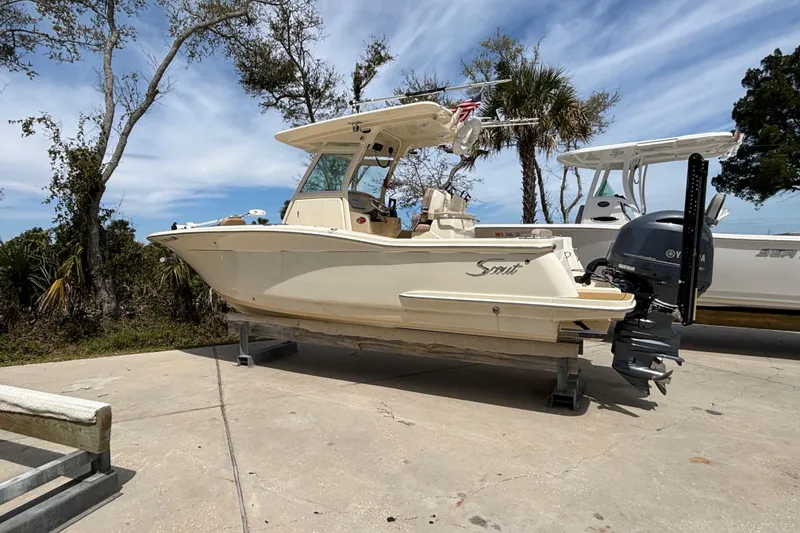The Image of 2016 Scout 255 LXF boat on a stand, surrounded by trees and clear sky. - 0