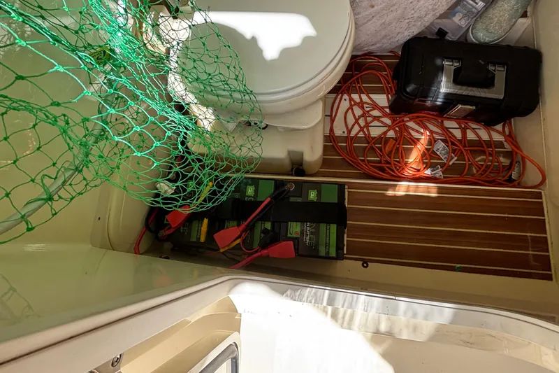 Slide: The Image of 2016 Scout 255 LXF boat interior with toilet, battery, and tools. - 18