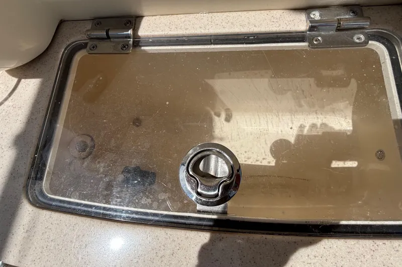 Slide: The Image of Hinged compartment lid on 2016 Scout 255 LXF boat, featuring a metal latch. - 2