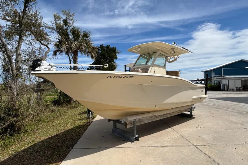 Slide: The Image of 2016 Scout 255 LXF boat on trailer, parked outdoors under blue sky. - 31