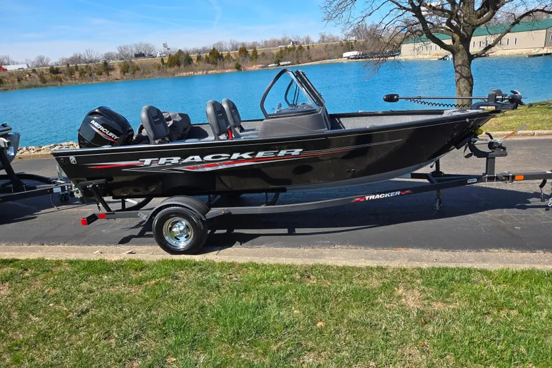Slide: The Image of 2024 Tracker Pro Guide V-16 WT boat on trailer by a lake. - 10
