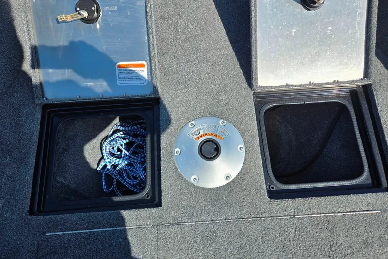 Slide: The Image of 2024 Tracker Pro Guide V-16 WT boat storage compartments with rope and warning label. - 18