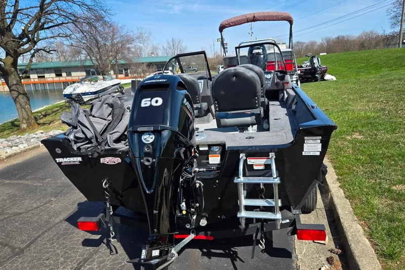 Slide: The Image of 2024 Tracker Pro Guide V-16 WT boat with Mercury 60 engine, parked near a lake. - 2