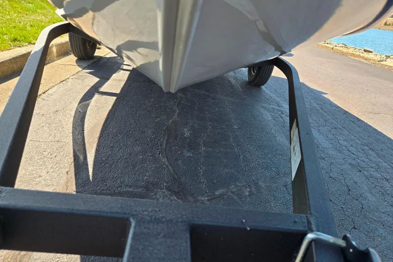 Slide: The Image of 2024 Tracker Pro Guide V-16 WT boat on trailer, parked on asphalt near water. - 8