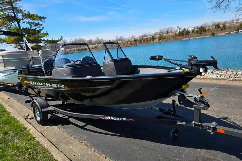 Slide: The Image of 2024 Tracker Pro Guide V-16 WT boat on trailer by a lake. - 9