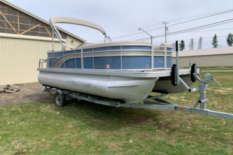 The Image of 2018 Bennington pontoon boat on trailer near a building. - 1