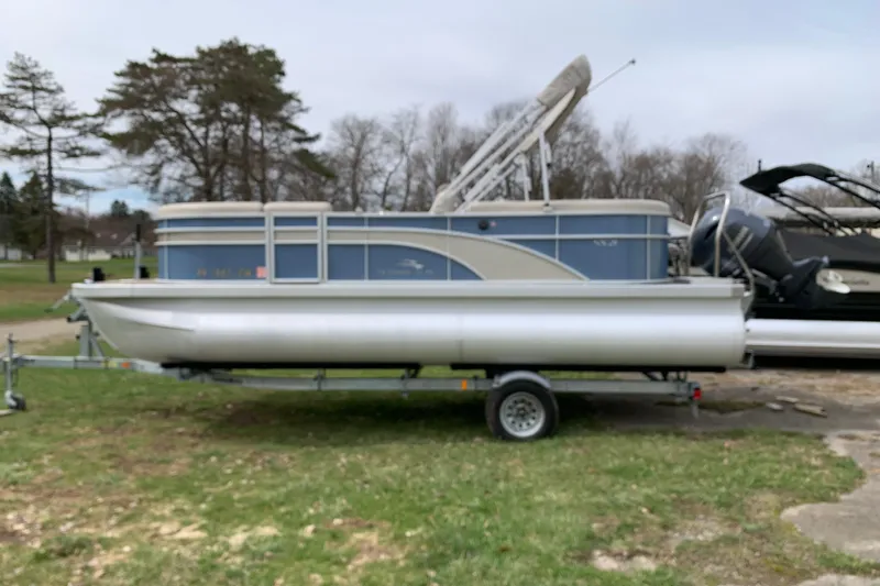 Slide: The Image of 2018 Bennington pontoon boat on trailer, parked on grass with trees in background. - 3