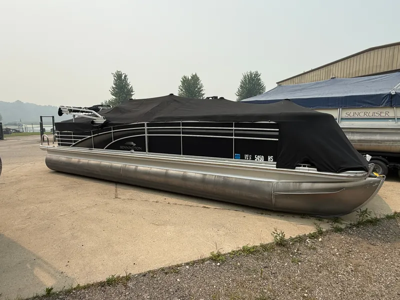 Slide: The Image of A 2010 Bennington 2550 RCW pontoon boat with a black cover, parked on a concrete lot. - 22