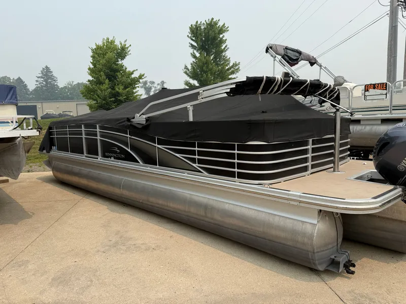 Slide: The Image of A 2010 Bennington 2550 RCW pontoon boat with a black cover, parked on a concrete lot. - 23