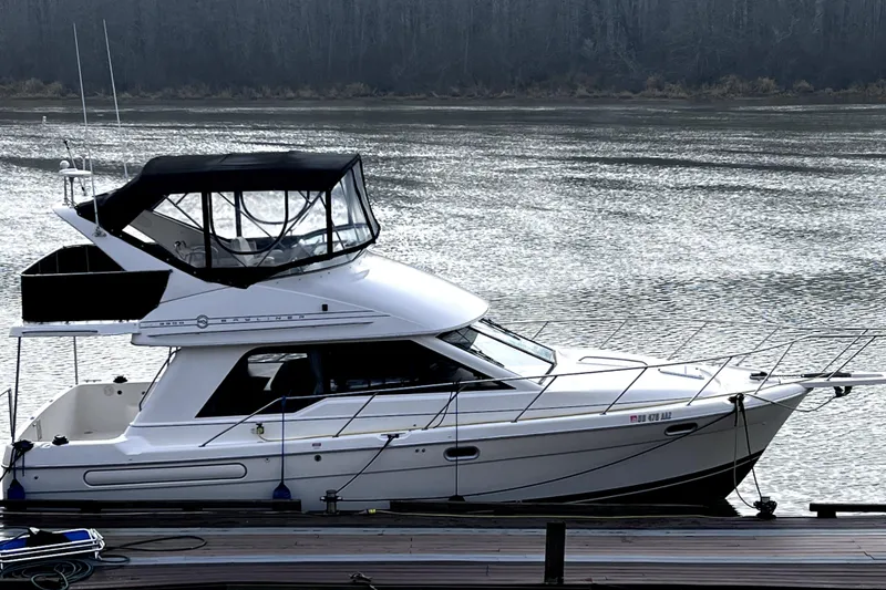 Slide: The Image of 1996 Bayliner 3388 Command Bridge Motoryacht docked on a serene river. - 3