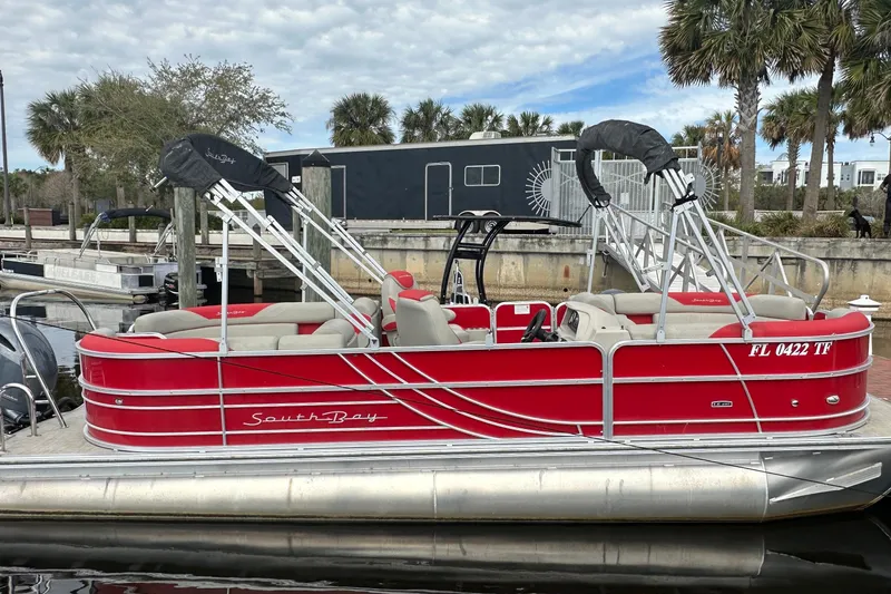The Image of 2022 South Bay Pontoons 24 LE Series Tri Hull, red, docked with palm trees in background. - 1