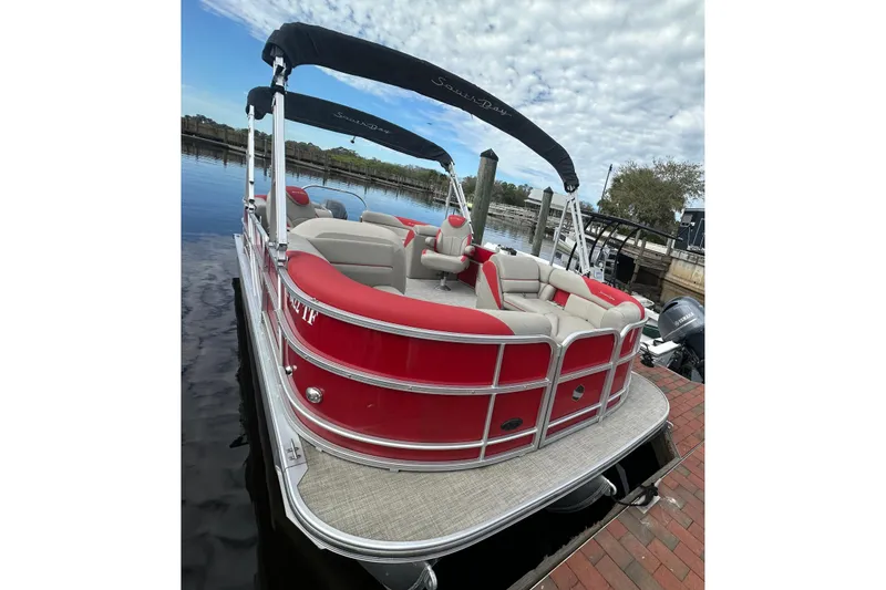 Slide: The Image of 2022 South Bay Pontoons 24 LE Series Tri Hull, red and beige, docked by the water. - 3