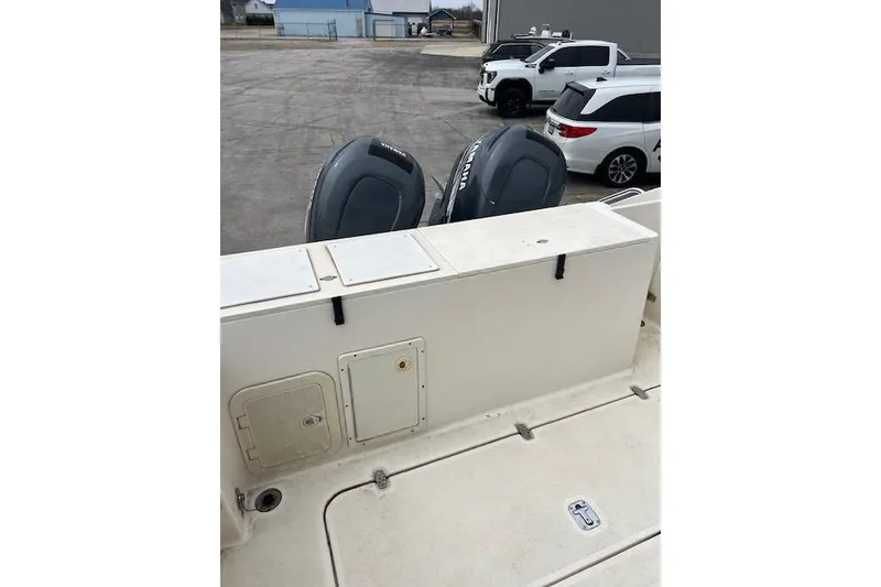 Slide: The Image of 2001 Pursuit 2670 Cuddy Console boat with dual outboard motors in a parking area. - 13