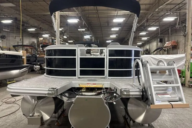 Slide: The Image of 2026 Bennington 22SXSR pontoon boat in a warehouse, rear view with ladder. - 3
