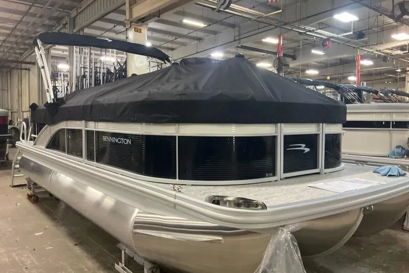 Slide: The Image of 2026 Bennington 22SXSR pontoon boat in a factory setting, covered and ready for delivery. - 7