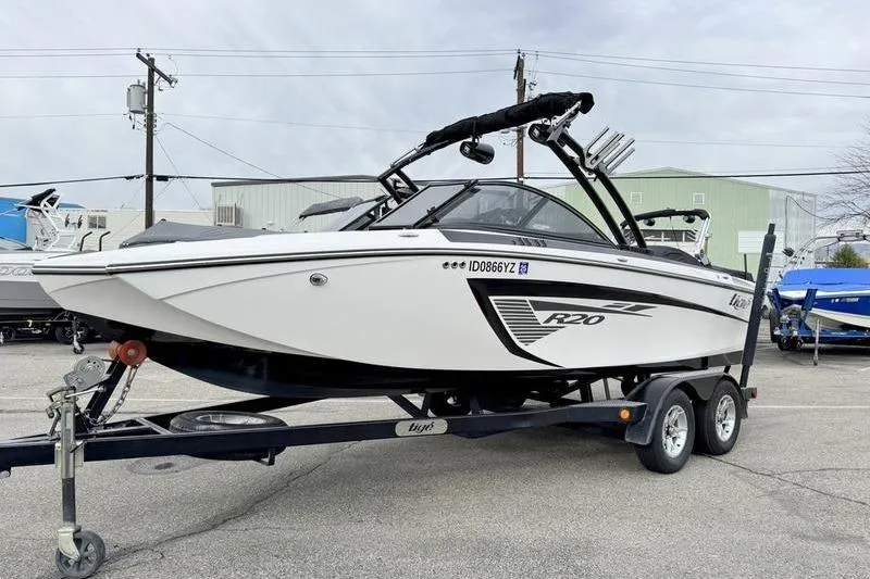 Slide: The Image of 2014 Tigé R20 boat on trailer, white with black accents, parked outdoors. - 4