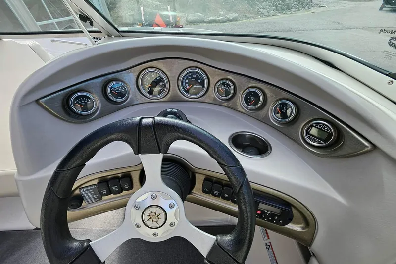 Slide: The Image of Steering wheel and dashboard of a 2011 Bryant 210 boat with gauges and controls. - 10