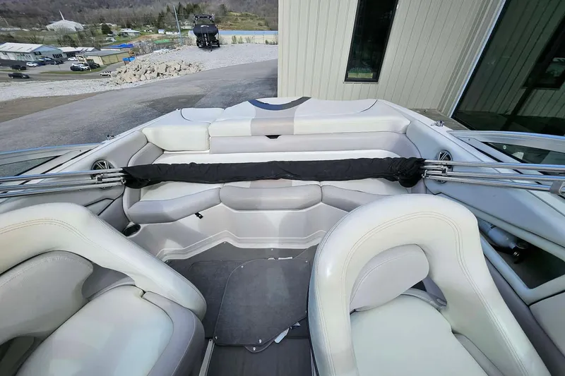 Slide: The Image of Interior of a 2011 Bryant 210 boat with white seating and a covered storage area. - 4