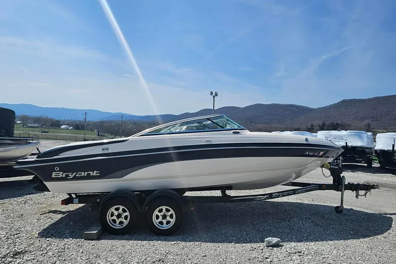 Slide: The Image of 2011 Bryant 210 boat on trailer, parked outdoors with mountains in background. - 7