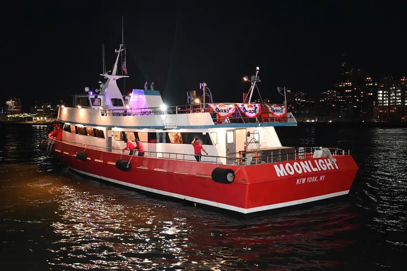 Slide: The Image of Red and white boat "Moonlight" on water at night, New York City skyline. - 3