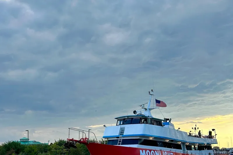 Slide: The Image of Commercial Steel 100 boat "Moon Light" with American flag under cloudy sky, 1985 model. - 4