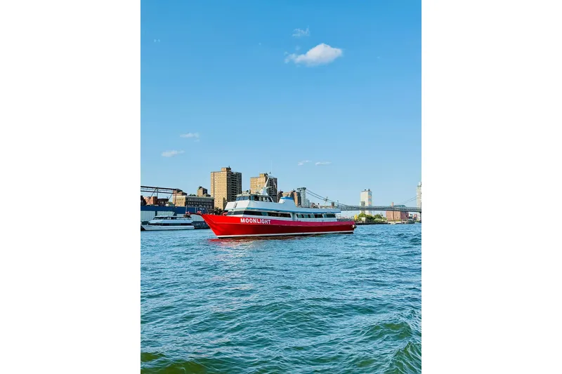 Slide: The Image of Red "Moonlight" boat on river with city skyline and bridge in background, clear blue sky. - 5