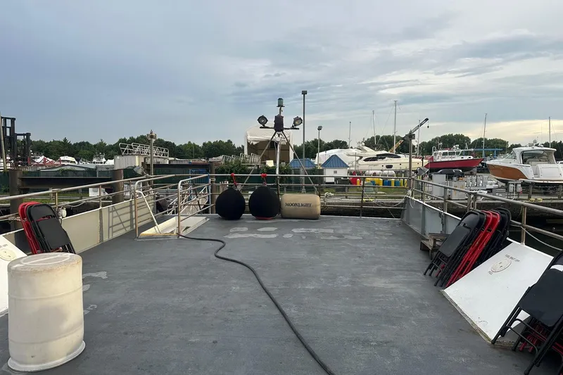 Slide: The Image of Deck of 1985 Custom Commercial Steel 100 boat docked at marina with chairs and equipment. - 7