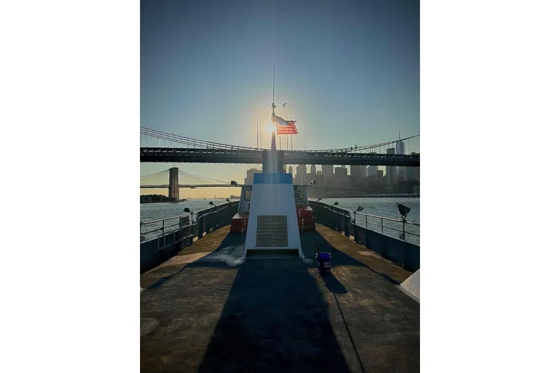 Slide: The Image of Boat deck with American flag, bridge, and city skyline at sunset. Custom Commercial Steel 100, 1985. - 8