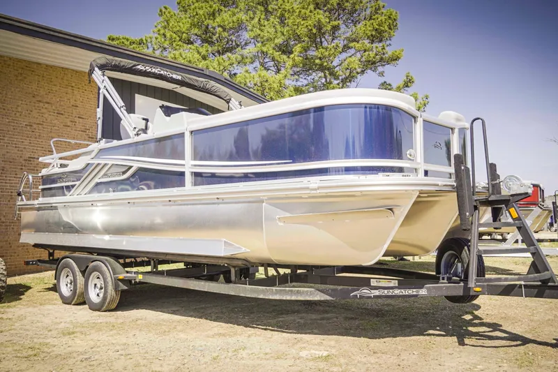 Slide: The Image of 2025 SunCatcher Fusion 324SS pontoon boat on trailer, parked outdoors. - 2