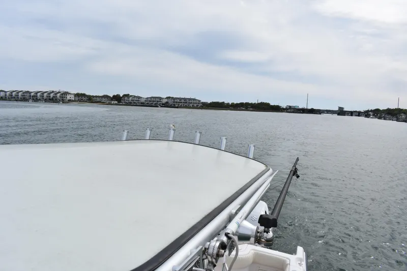 Slide: The Image of Grady-White Advance 247 boat on calm waters, coastal buildings in background, overcast sky. - 27