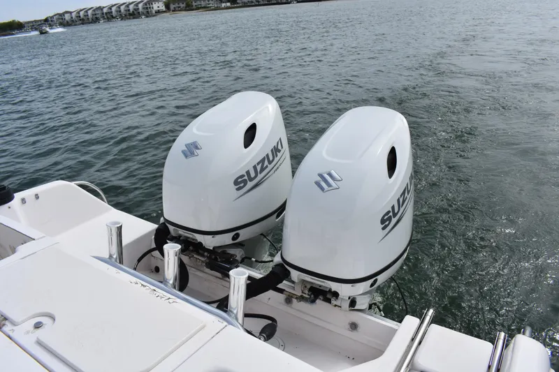 Slide: The Image of Twin Suzuki outboard motors on a 2001 Grady-White Advance 247 boat, docked by the water. - 29