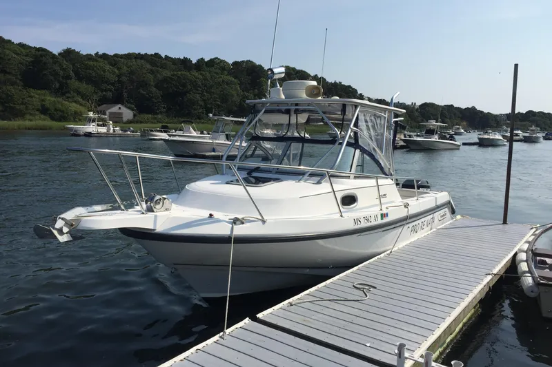 Slide: The Image of Boston Whaler 235 Conquest 2000 docked on a sunny day with other boats nearby. - 2