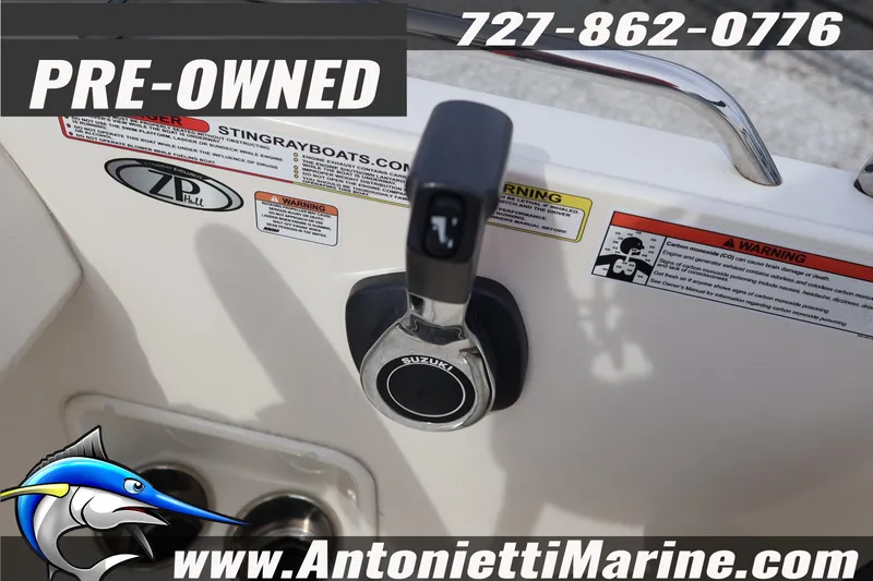Slide: The Image of Pre-owned 2023 Stingray 212 SC boat control panel with warning labels and contact information. - 24