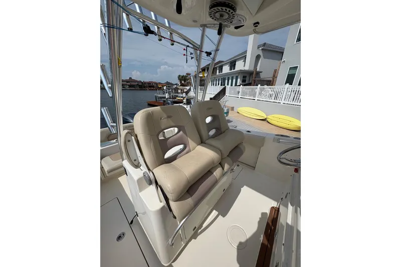 Slide: The Image of 2016 Cobia 296 Center Console boat with beige seating, docked near waterfront homes. - 17